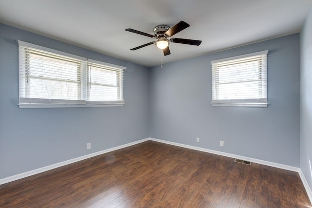 empty room featuring ceiling fan, wood finished floors, visible vents, and baseboards