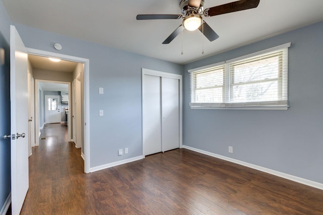 unfurnished bedroom with ceiling fan, dark wood-style flooring, a closet, and baseboards