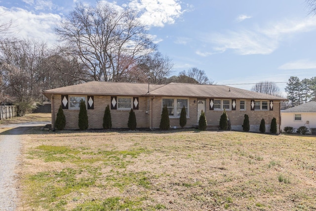 ranch-style home featuring brick siding, a front yard, and fence