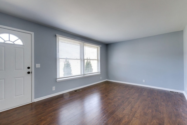 foyer entrance with visible vents, dark wood finished floors, and baseboards