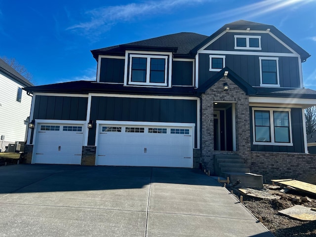 view of front of home with an attached garage, central AC unit, board and batten siding, stone siding, and driveway