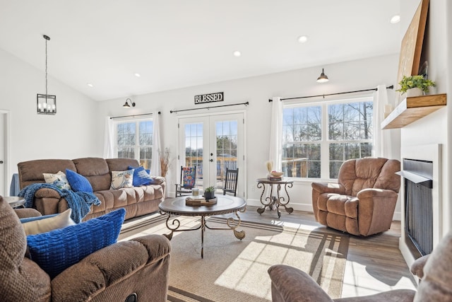 living area featuring lofted ceiling, recessed lighting, a fireplace, wood finished floors, and french doors