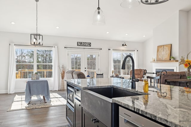 kitchen with open floor plan, wood finished floors, light stone countertops, stainless steel appliances, and a fireplace