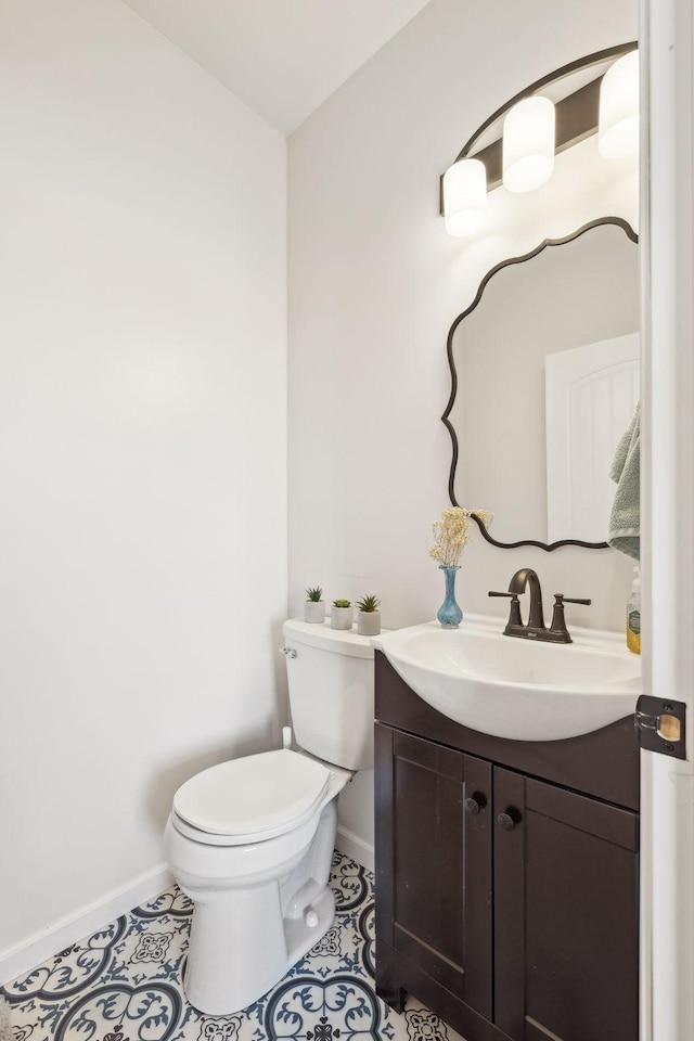 half bathroom featuring toilet, tile patterned flooring, vanity, and baseboards