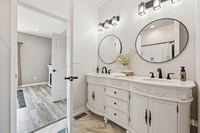 bathroom with visible vents, a sink, baseboards, and double vanity