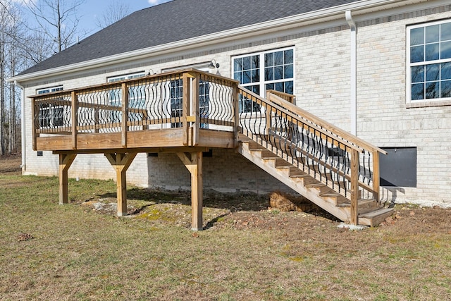 rear view of property featuring brick siding, a yard, roof with shingles, a deck, and stairs