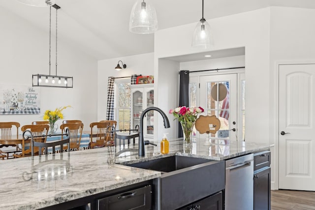 kitchen with wood finished floors, decorative light fixtures, light stone countertops, vaulted ceiling, and a sink