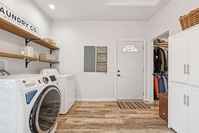 laundry area with washer and clothes dryer, cabinet space, light wood-type flooring, electric panel, and baseboards