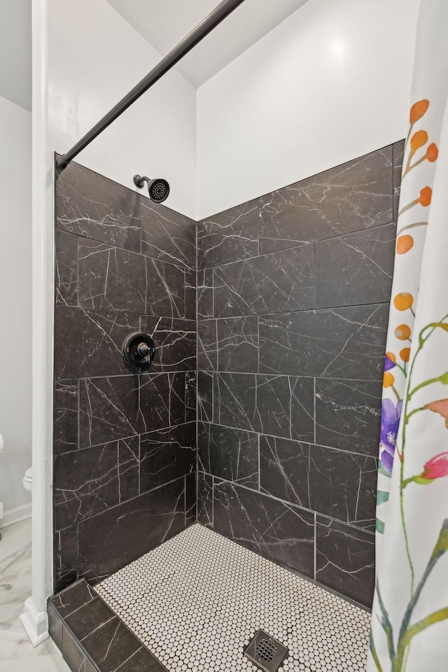 bathroom with marble finish floor, a tile shower, and toilet