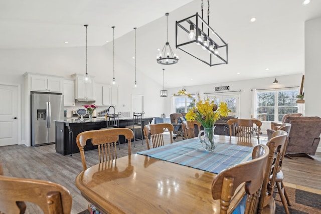 dining room with high vaulted ceiling, light wood-type flooring, and a healthy amount of sunlight