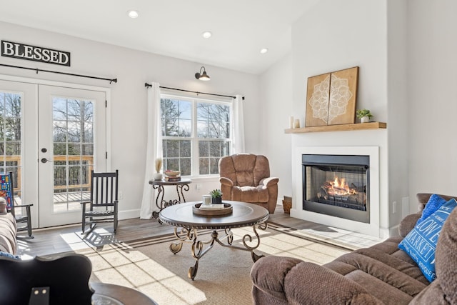 living room featuring french doors, lofted ceiling, recessed lighting, a glass covered fireplace, and wood finished floors