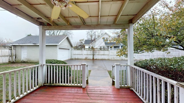 wooden terrace featuring a garage, an outbuilding, and fence