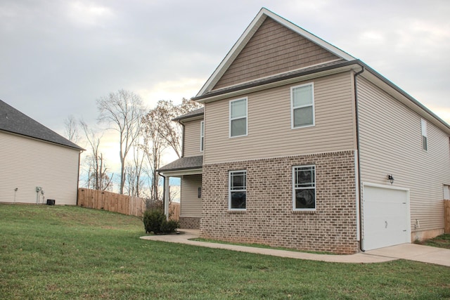 back of property with a garage, brick siding, fence, a yard, and concrete driveway