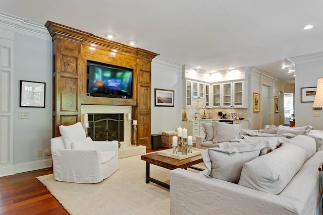 living area featuring a fireplace, baseboards, crown molding, and wood finished floors