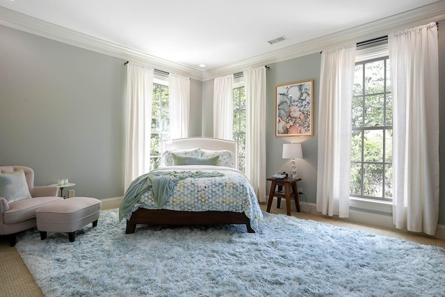 carpeted bedroom featuring baseboards, multiple windows, visible vents, and crown molding