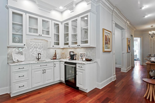 bar with dark wood-style floors, ornamental molding, a sink, and tasteful backsplash