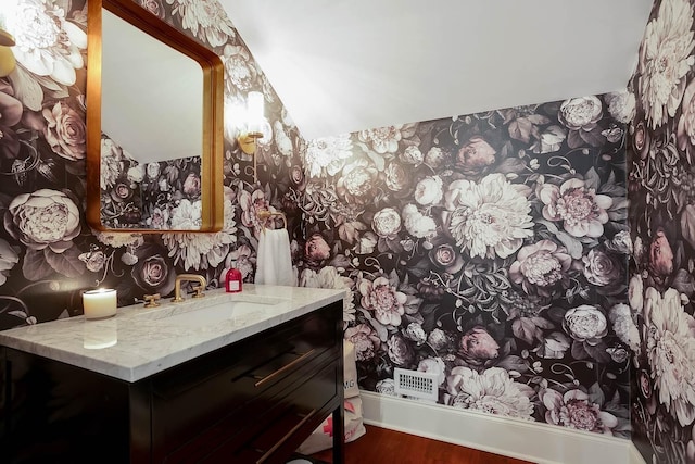 bathroom featuring wallpapered walls, wood finished floors, and vanity