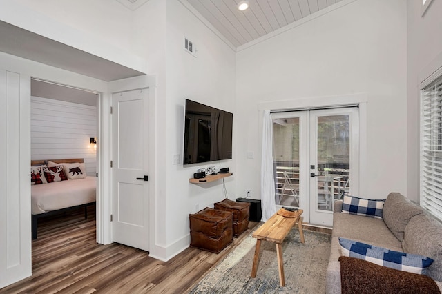 living area with high vaulted ceiling, wood finished floors, visible vents, french doors, and crown molding