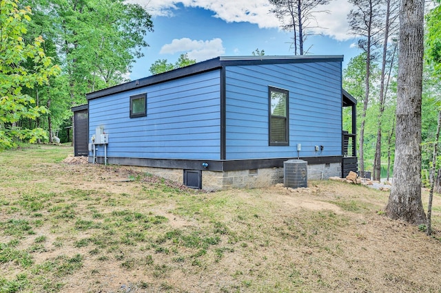 view of side of home with crawl space, central AC unit, and a yard