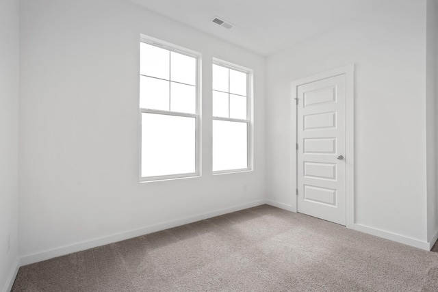 unfurnished room with carpet floors, visible vents, and baseboards