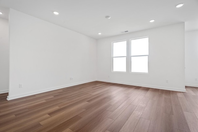 empty room featuring recessed lighting, visible vents, baseboards, and wood finished floors