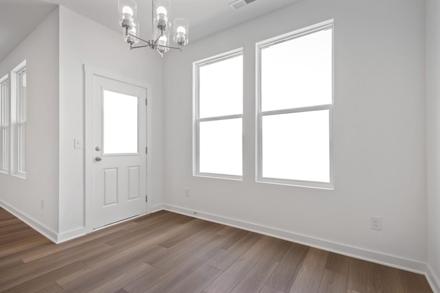 foyer with dark wood-type flooring, visible vents, baseboards, and an inviting chandelier