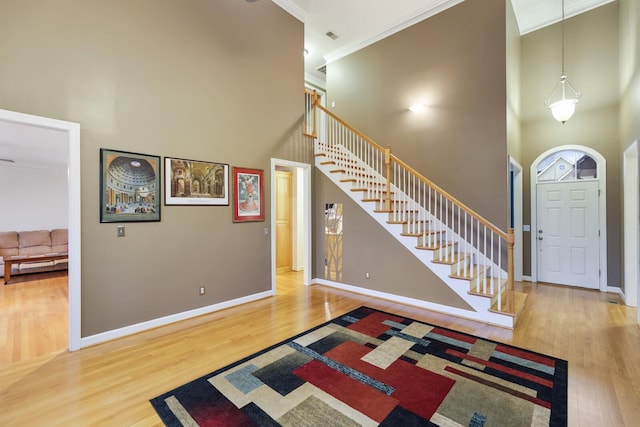 entrance foyer featuring a high ceiling, crown molding, and wood finished floors