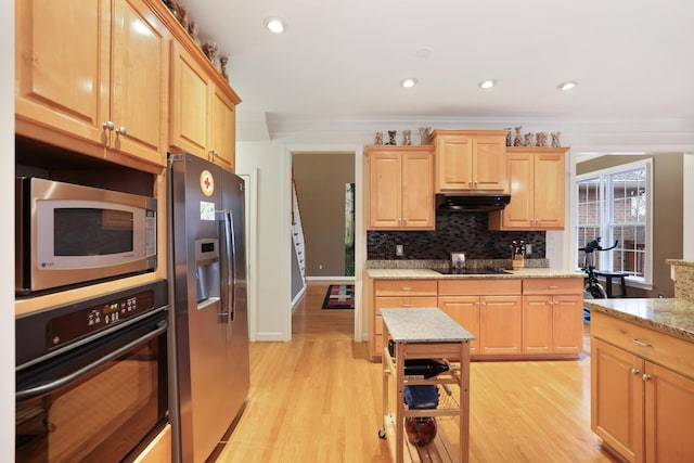 kitchen featuring black appliances, light wood-style floors, decorative backsplash, and under cabinet range hood