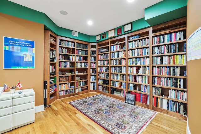 living area featuring recessed lighting, bookshelves, visible vents, and wood finished floors