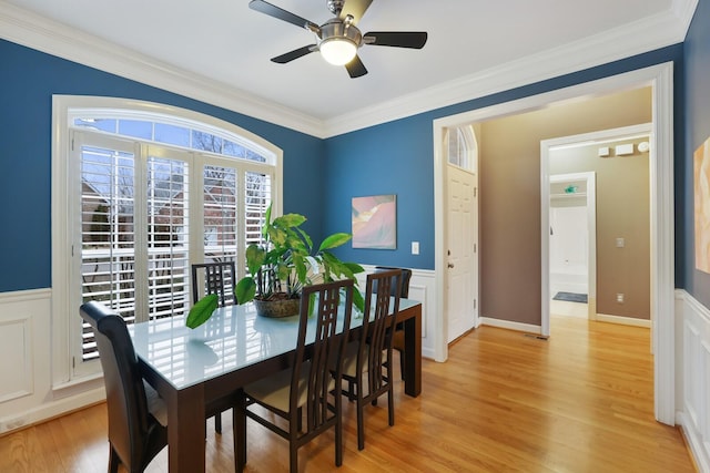 dining room featuring light wood-style floors, crown molding, and wainscoting