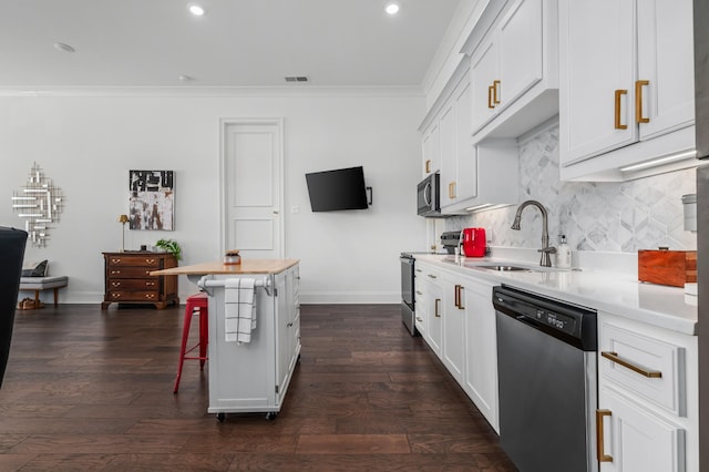 kitchen with tasteful backsplash, appliances with stainless steel finishes, ornamental molding, light countertops, and a sink