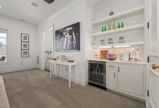 bar featuring light colored carpet, beverage cooler, a sink, ornamental molding, and a bar