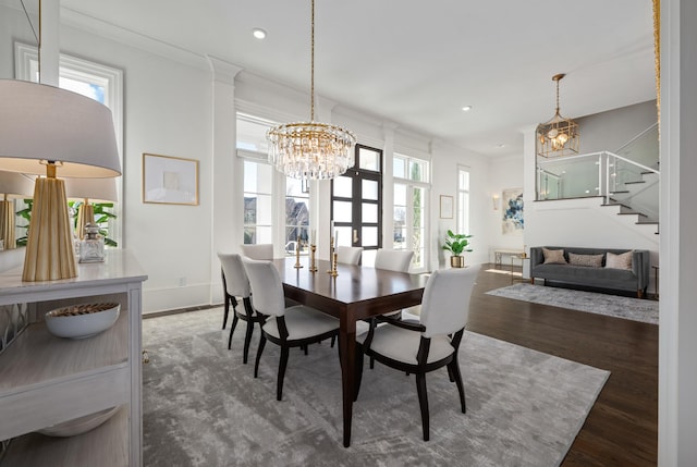 dining space with a chandelier, a wealth of natural light, stairway, and wood finished floors