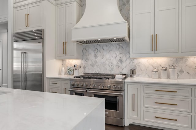 kitchen featuring premium appliances, backsplash, and custom range hood