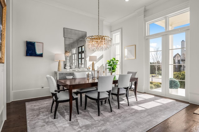 dining area featuring a healthy amount of sunlight, a chandelier, wood finished floors, and ornamental molding