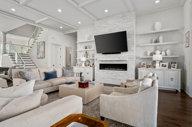 living area with built in shelves, a fireplace, crown molding, dark wood-type flooring, and stairs