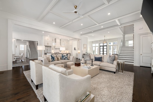 living room featuring ornate columns, stairway, coffered ceiling, and dark wood finished floors