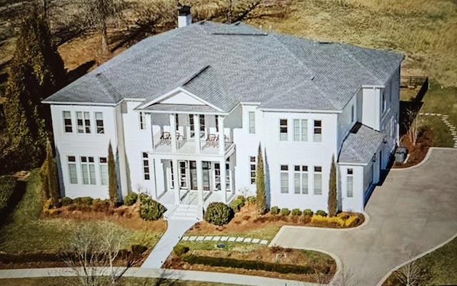 view of front of home featuring a chimney and a balcony