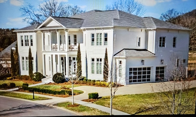 back of house featuring concrete driveway, a balcony, and an attached garage