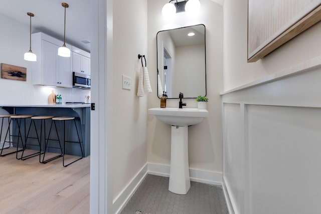 bathroom with decorative backsplash, baseboards, and wood finished floors