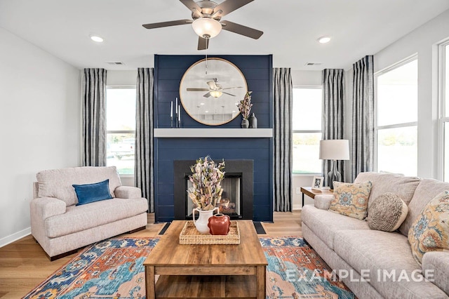 living room featuring a large fireplace, wood finished floors, and a healthy amount of sunlight