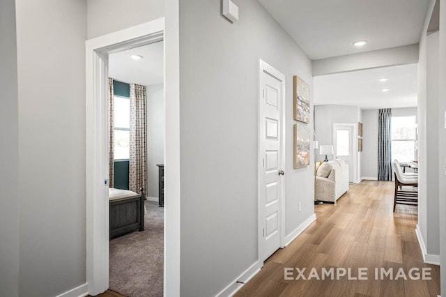 hallway featuring baseboards, recessed lighting, and light wood-style floors