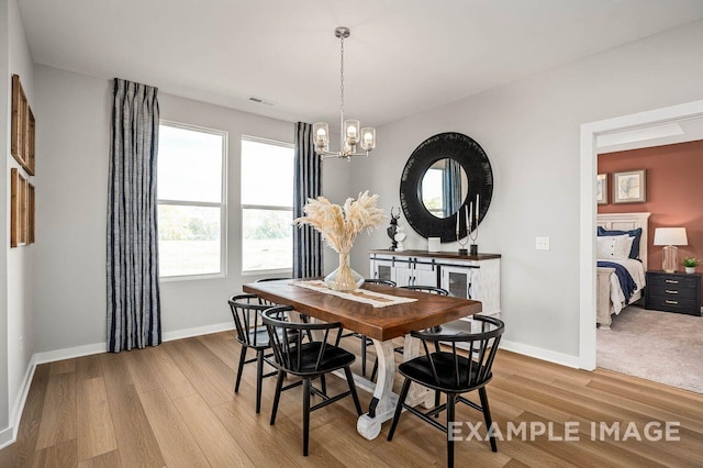 dining area featuring a chandelier, light wood-style flooring, visible vents, and baseboards