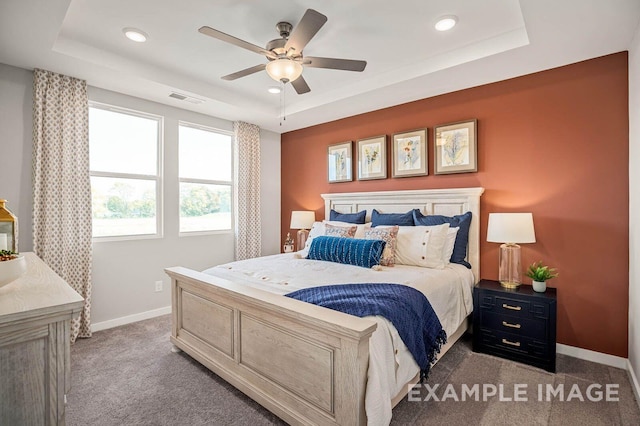 carpeted bedroom featuring a raised ceiling, visible vents, and baseboards