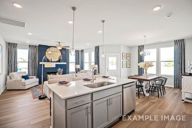 kitchen featuring a large fireplace, a sink, visible vents, gray cabinets, and dishwasher