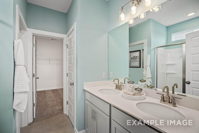 full bathroom featuring double vanity, a stall shower, a spacious closet, and a sink