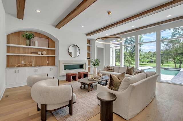 living room with light wood-style flooring, built in shelves, a fireplace, beam ceiling, and recessed lighting