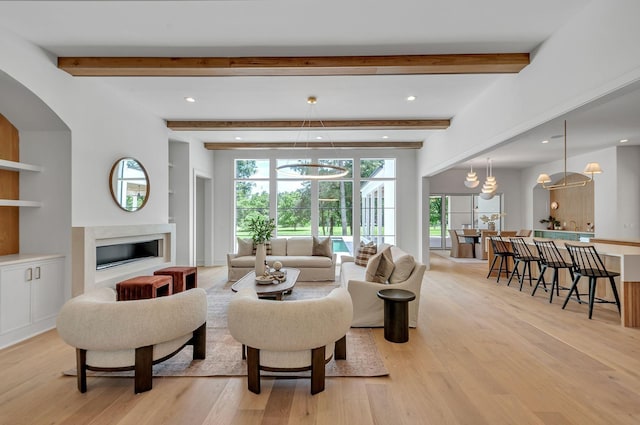 living area featuring built in features, beam ceiling, recessed lighting, a premium fireplace, and light wood-style floors