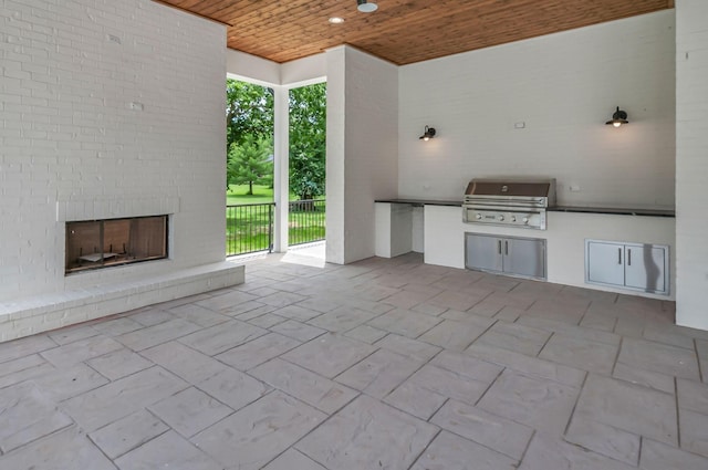 view of patio / terrace with an outdoor brick fireplace, an outdoor kitchen, and area for grilling