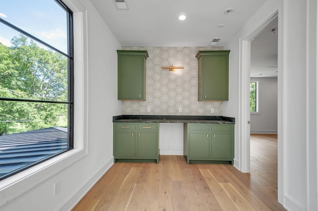 kitchen featuring dark countertops, visible vents, backsplash, light wood-type flooring, and green cabinetry